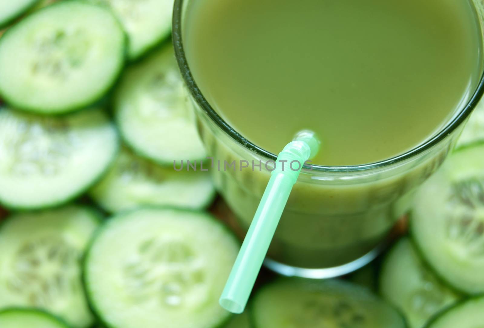 Fresh vegetable detox juice with cucumber slices in the background