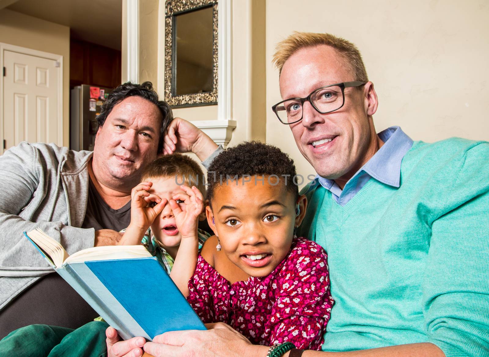 Attractive gay couple reads a book to their children