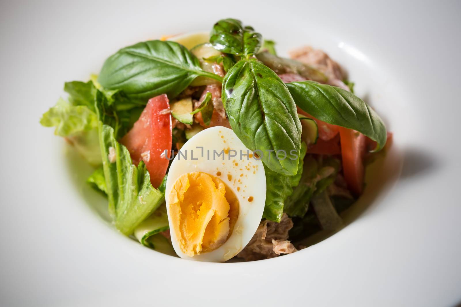 Closeup of plate of spring mix salad with strawberry, eggs and tuna