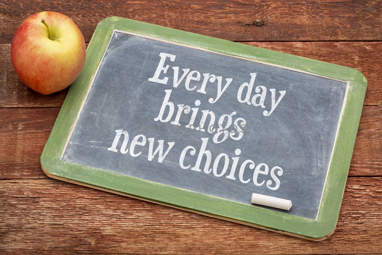Every day brings new choices - motivational positive words on a slate blackboard against red barn wood