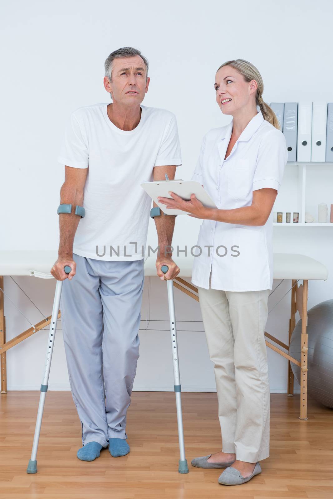 Man with crutch speaking with his doctor in medical office