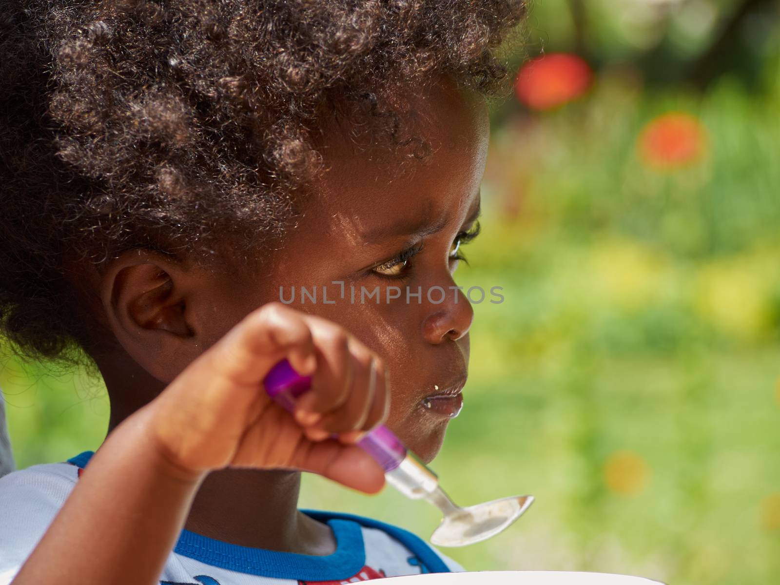 Adorable black African baby eating with food feeled face