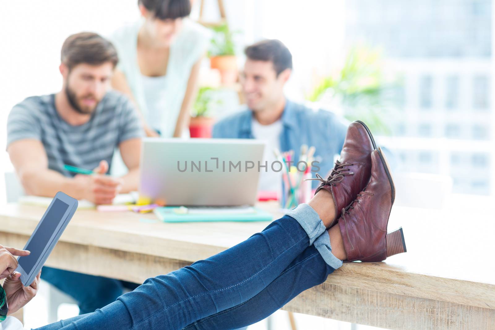 Young casual woman with feet on the table  by Wavebreakmedia