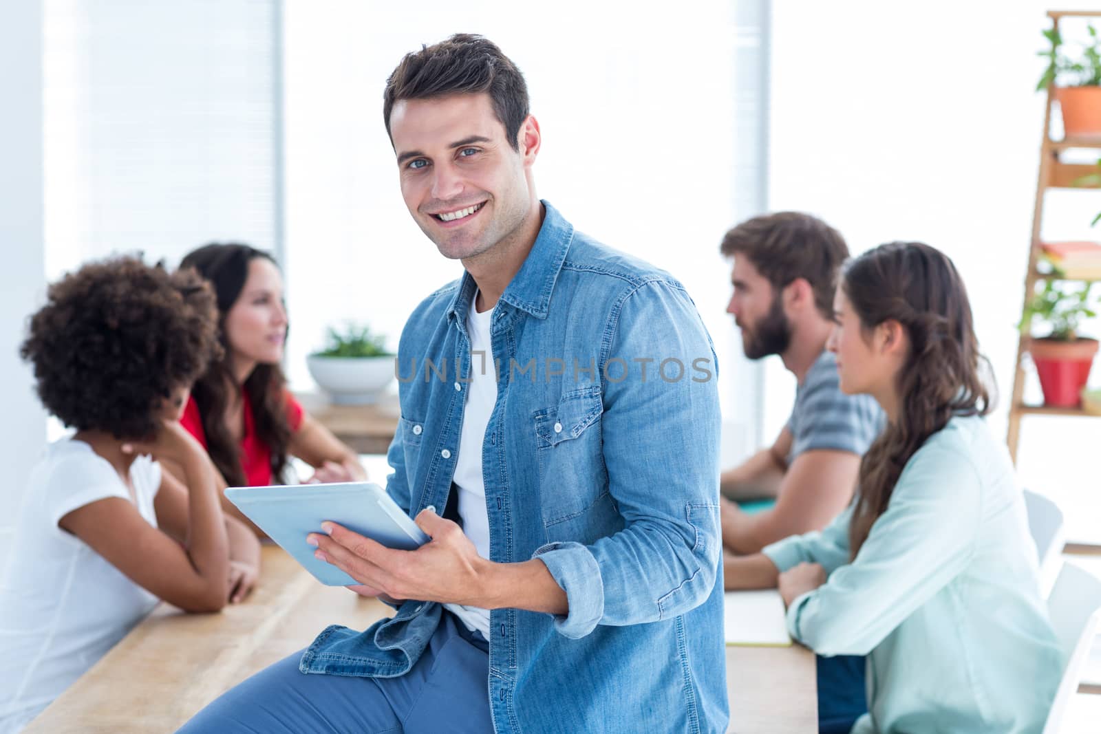 Smiling young businessman using a tablet  by Wavebreakmedia