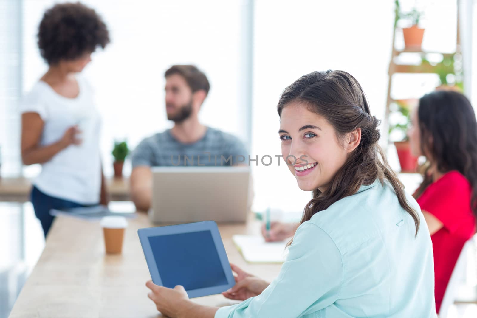 Smiling businesswoman using tablet while her team is working 