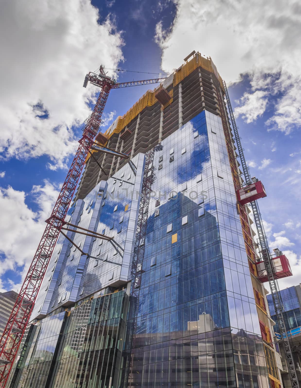 Construction site of new glass skyscraper with cranes on sky background