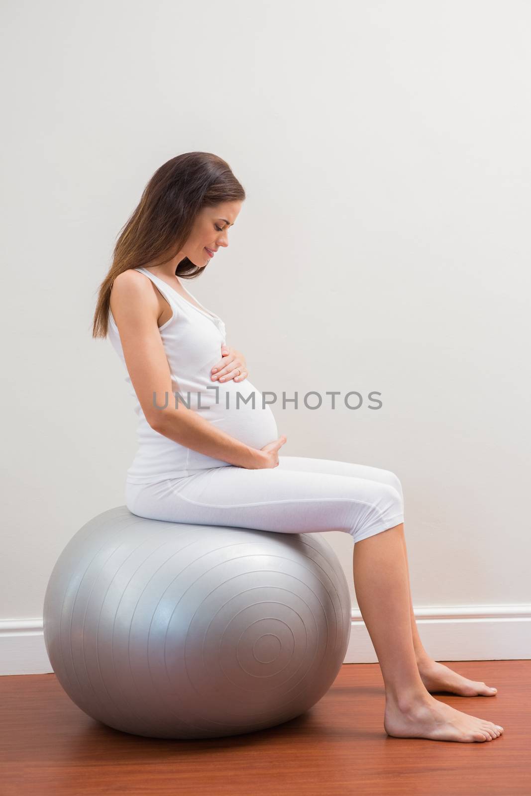 Happy pregnancy sitting on exercice ball in a room 
