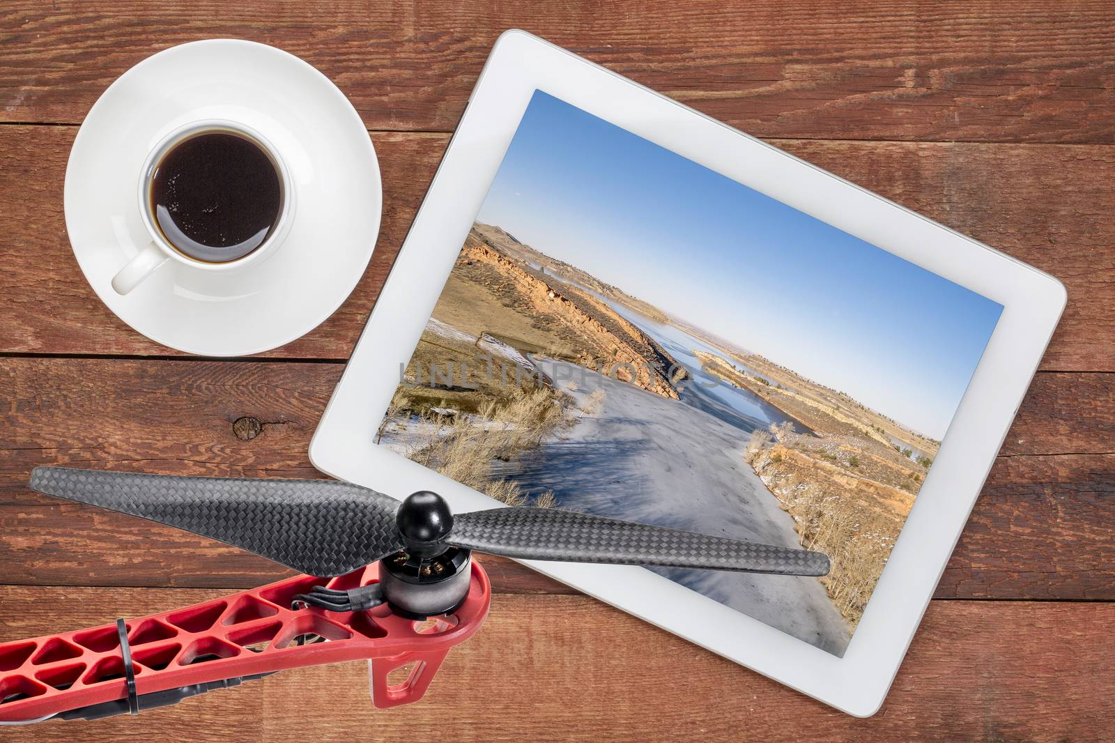 aerial landscape photography concept - reviewing aerial pictures of  the Horsetooth Reservoir in Colorado on a digital tablet with a drone rotor in foreground, screen picture copyright by the photographer