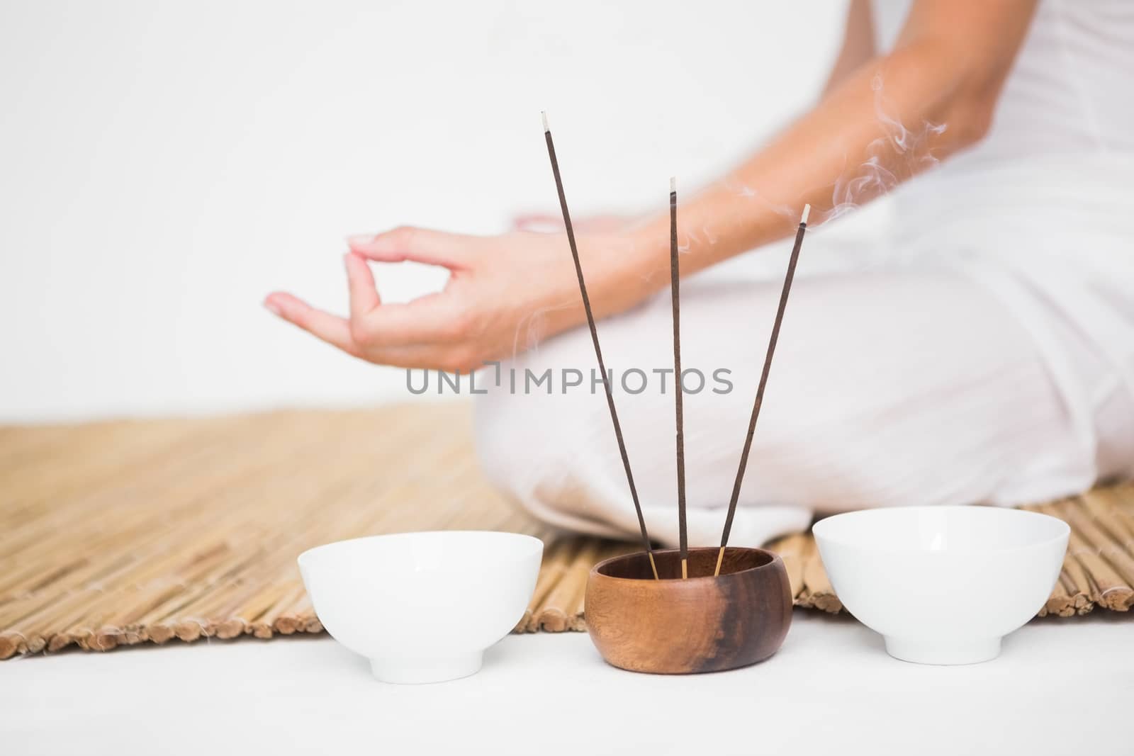 Fit woman meditating on bamboo mat on white background