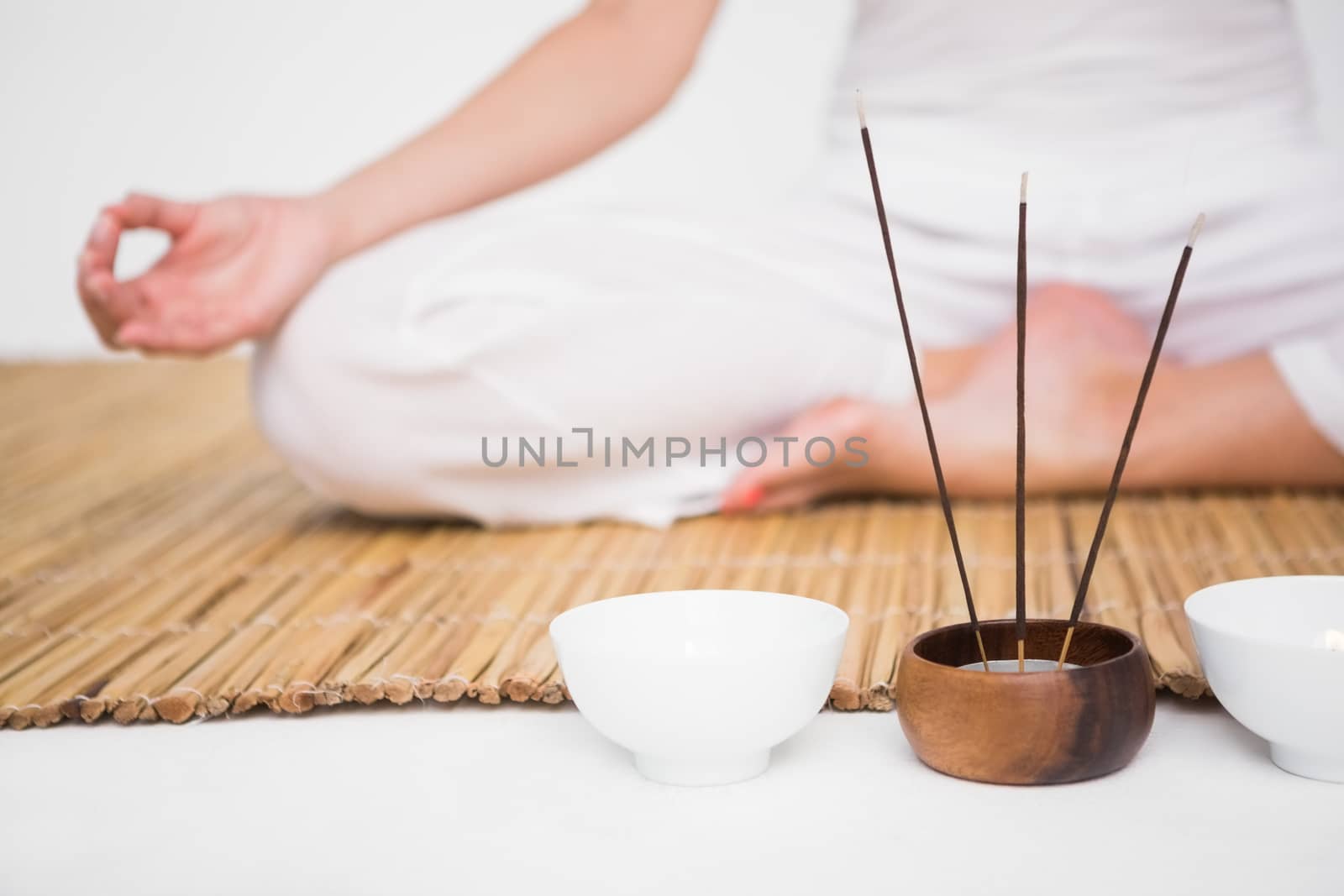 Fit woman meditating on bamboo mat on white background