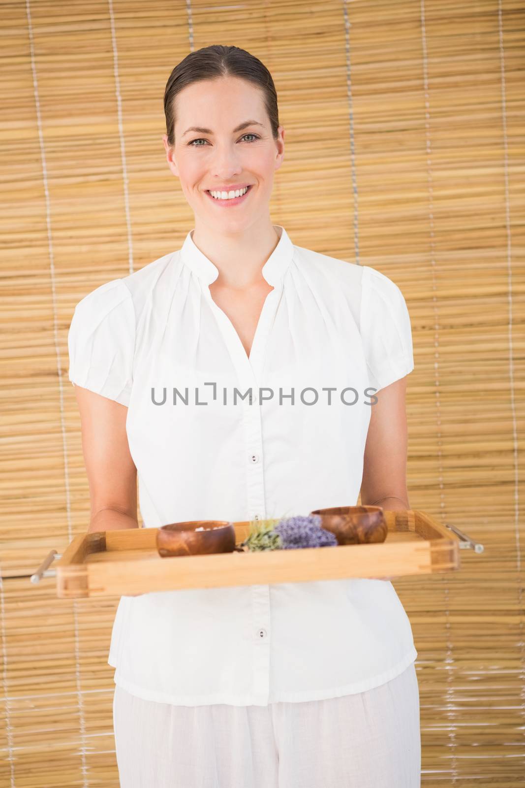 Portrait of a smiling beauty therapist holding tray of beauty treatments at the spa