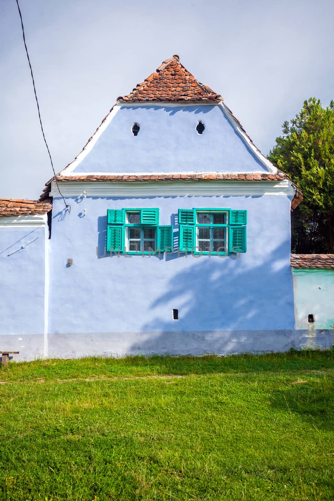 Viscri, Romania - June 23, 2013: Blue painted traditional house with green windows from Viscri village in Transylvania, Romania