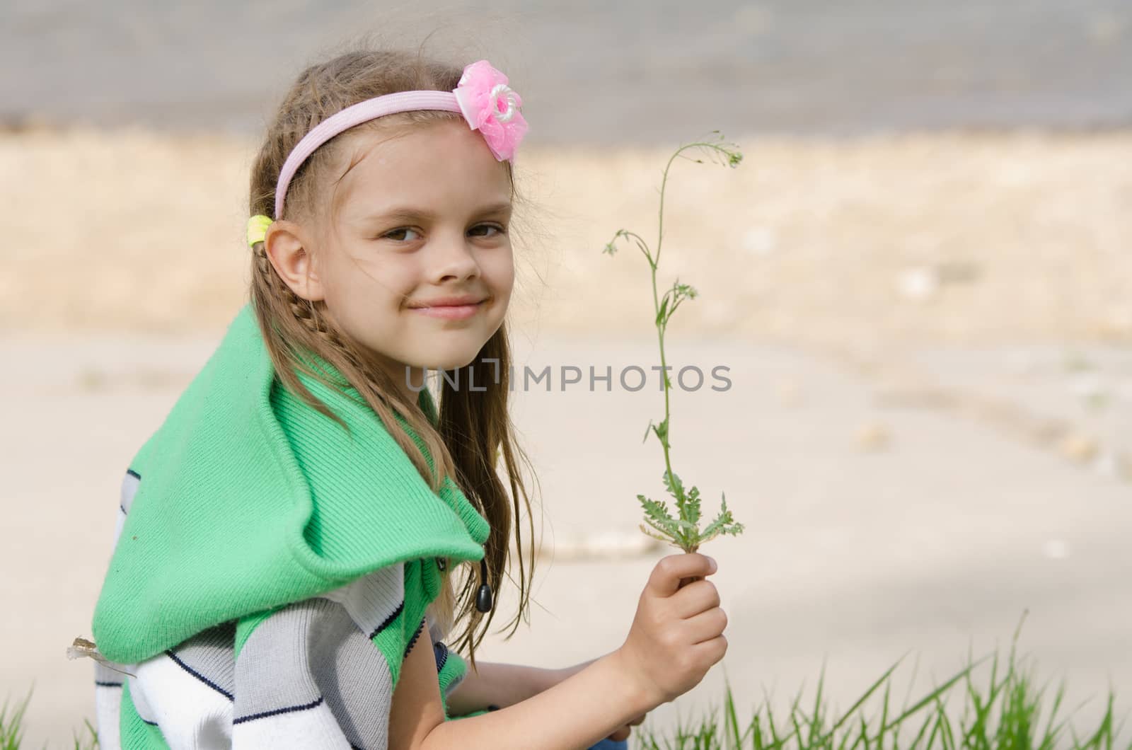 Girl happily plucked a blade of grass for a herbarium