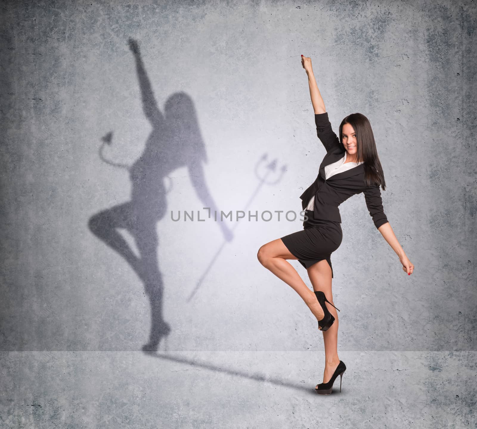 Businesswoman with shadow showing devil side on wall texture background, looking at camera