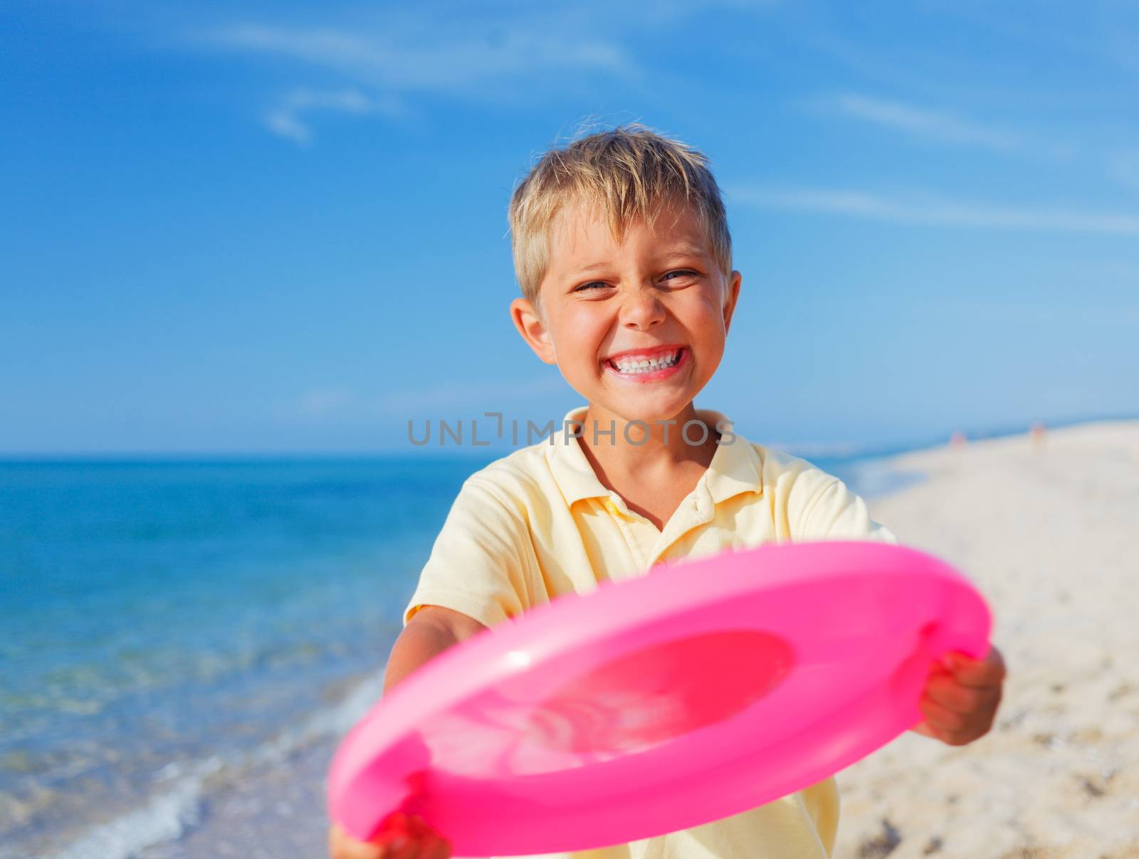 Cute little boy playing frisbee on beach