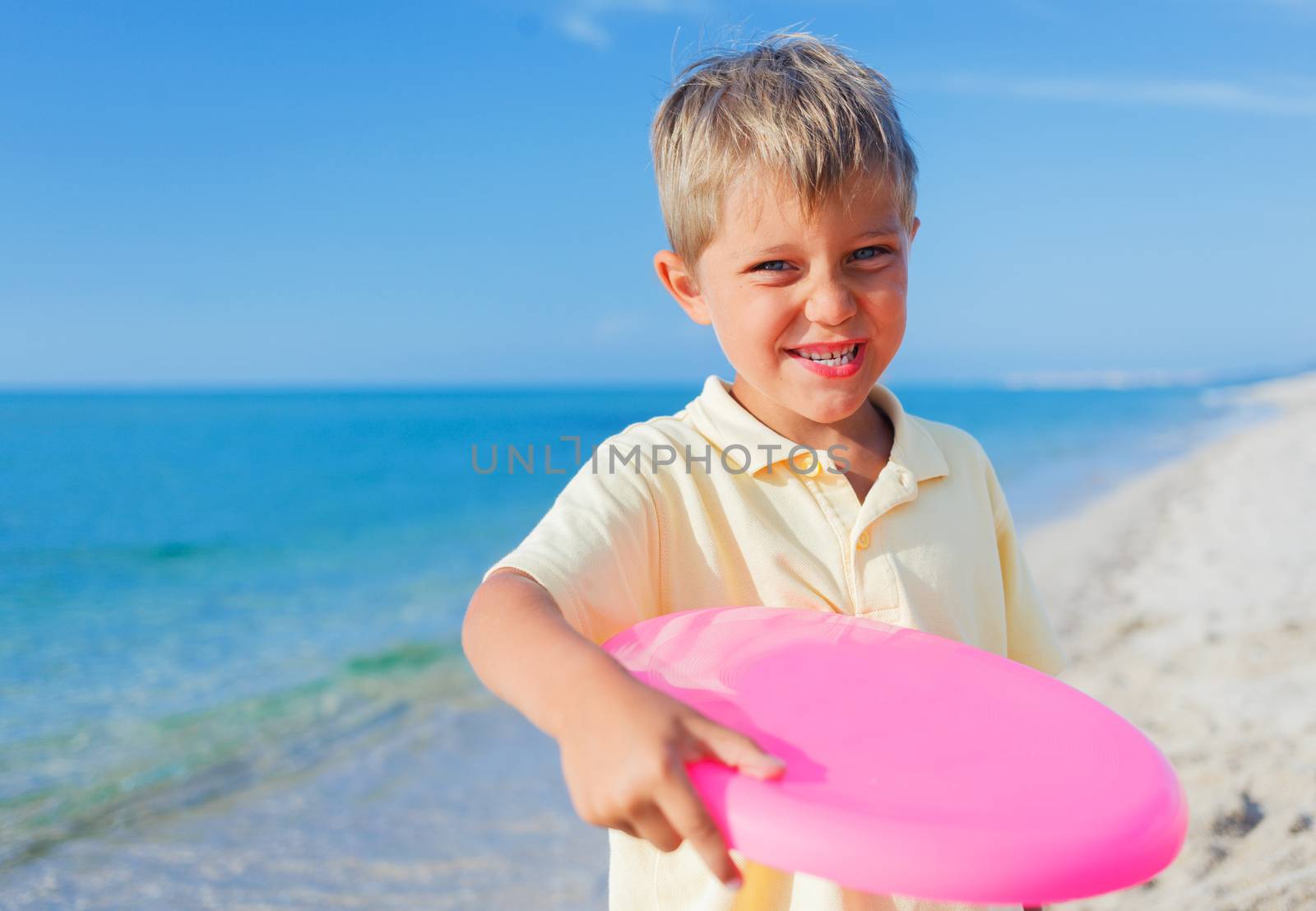 Cute little boy playing frisbee on beach