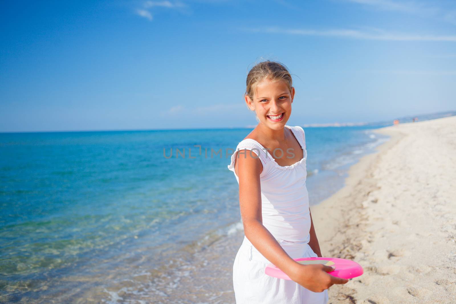 Happy cute girl playing frisbee on beach