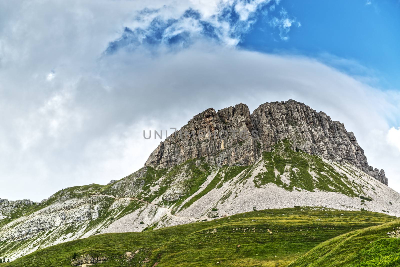 Landscape of the Mountain Castellazzo seen from Rolle Passwith clouds and blue sky background, Dolomites, Trentino - Italy