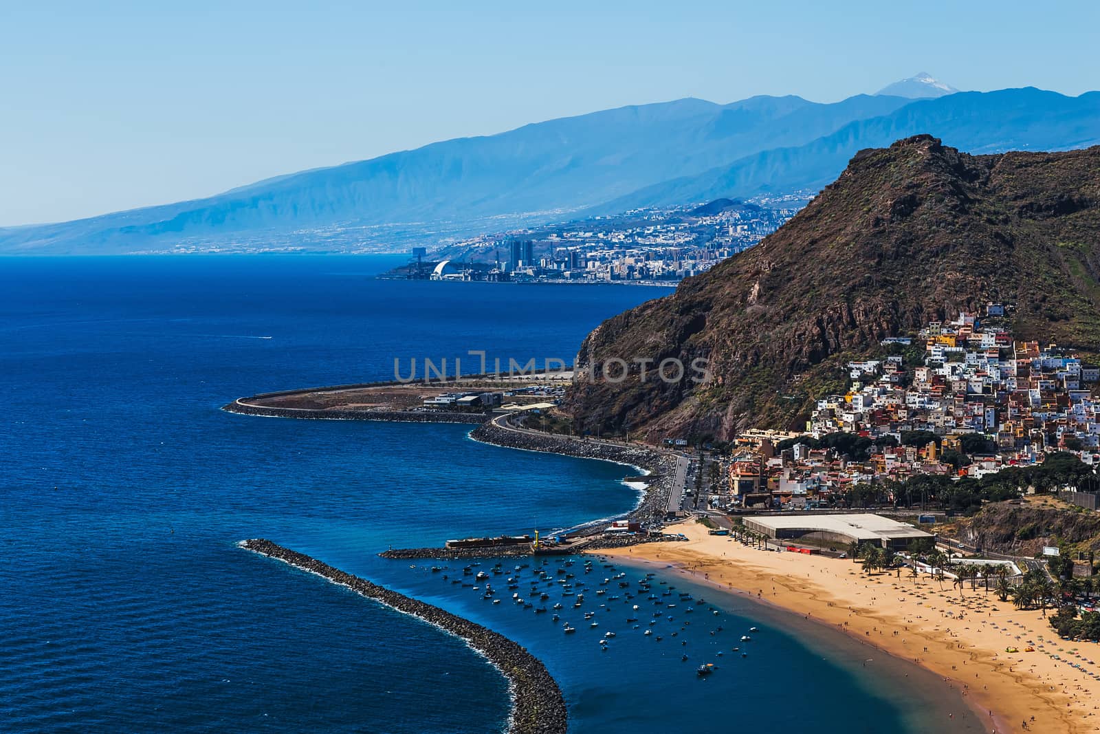 View to Santa Cruz city and beach or playa Las Teresitas on coast or shore of the Atlantic ocean on Tenerife Canary island, Spain at spring or summer. Teide volcano at background