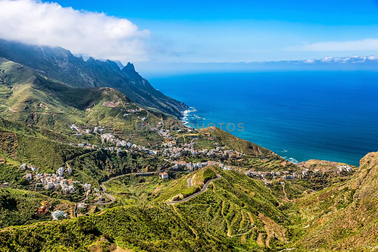 Mountain and clouds with small city or village and sky horizon landscape near the coast or shore of Atlantic ocean in Tenerife Canary island, Spain
