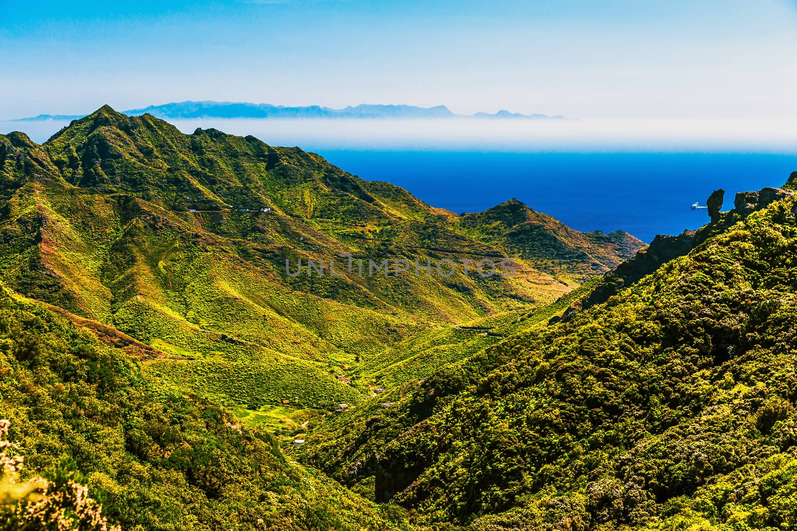 Green mountains and blue sky with island on skyline or horizon and ocean landscape in Tenerife Canary island, Spain