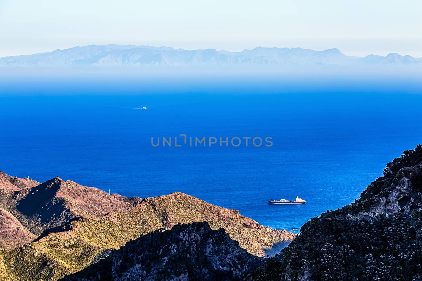 Cargo ship in the bay. Aerial view from rock or mountain. Island on horizon