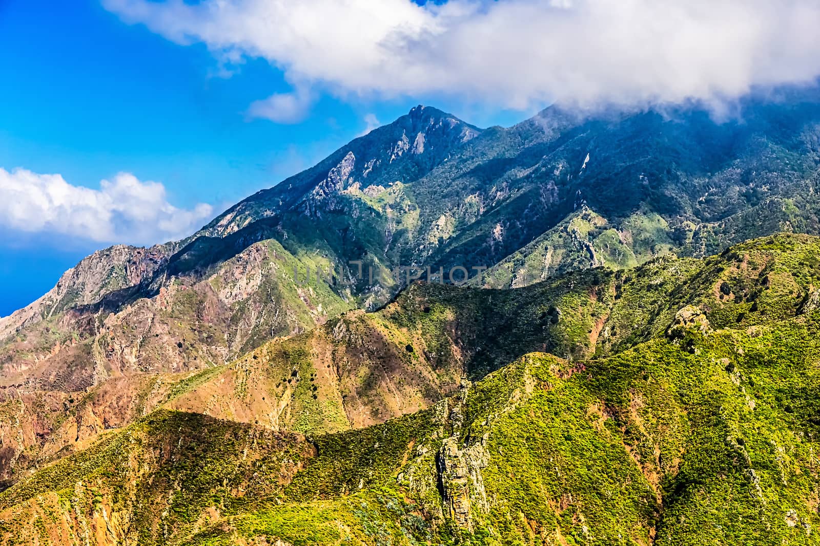 Green rocks with white clouds on blue sky landscape in Tenerife island, Spain