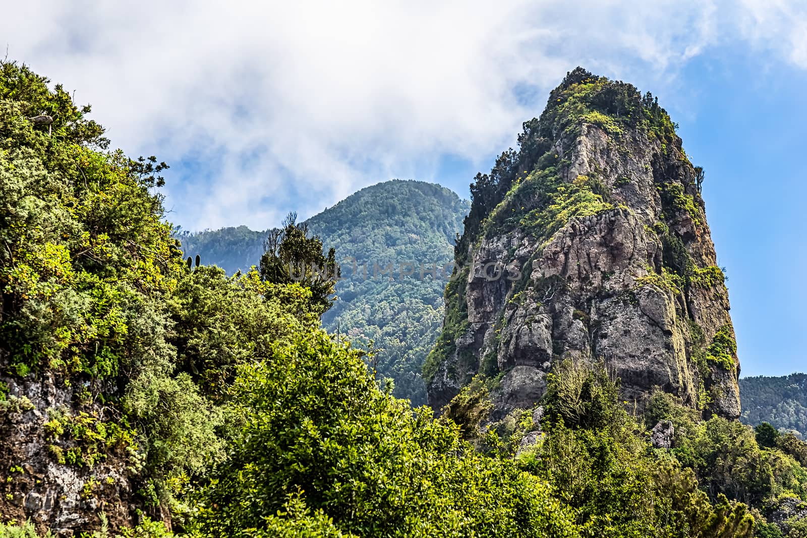 Rocks in green mountain with clouds in sky. Tenerife Canary island, Spain