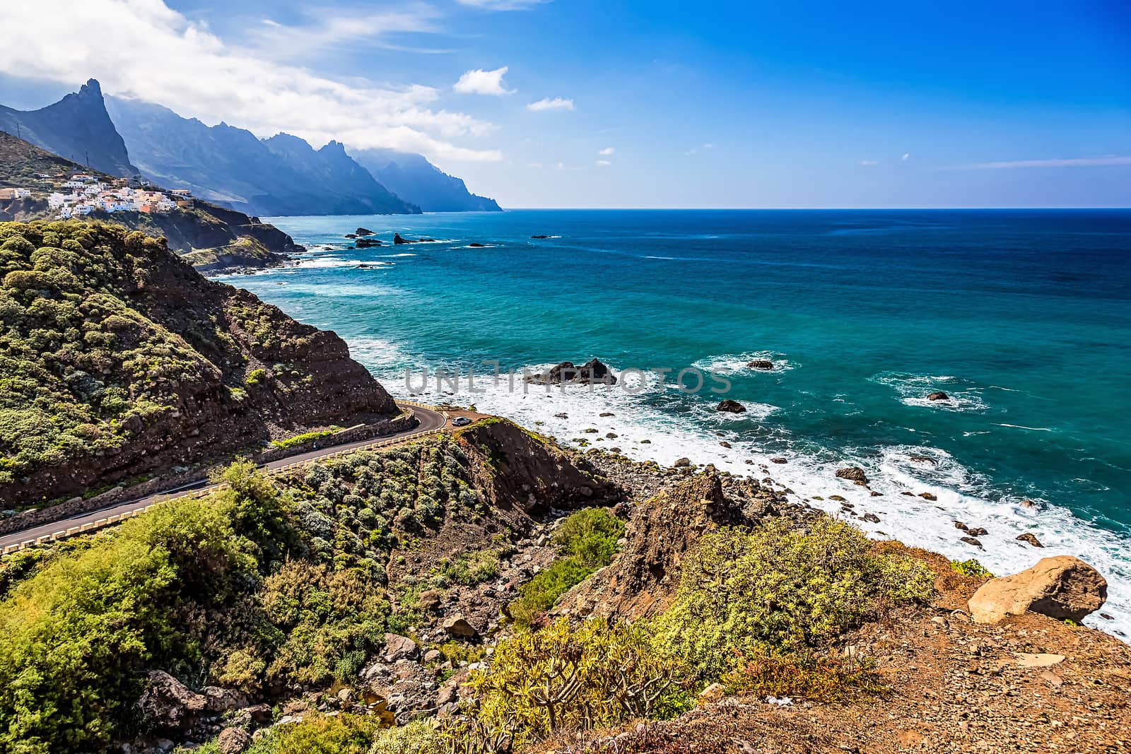 Road to coast of Atlantic ocean beach with mountains or rocks and blue sky with clouds and skyline or horizon in Tenerife Canary island, Spain at spring or summer