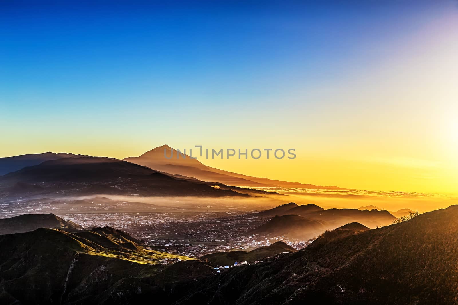 Sunset in mountains and blue sky with fog or haze and Teide volcano on background in Tenerife Canary island, Spain at spring or summer