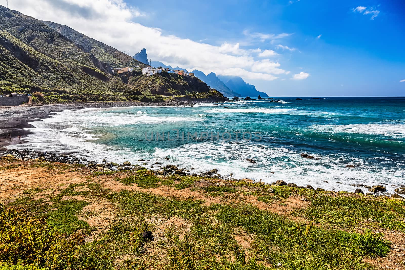 Coast or shore of Atlantic ocean with green mountain or rock and  sky with clouds and skyline or horizon in Tenerife Canary island, Spain at spring or summer