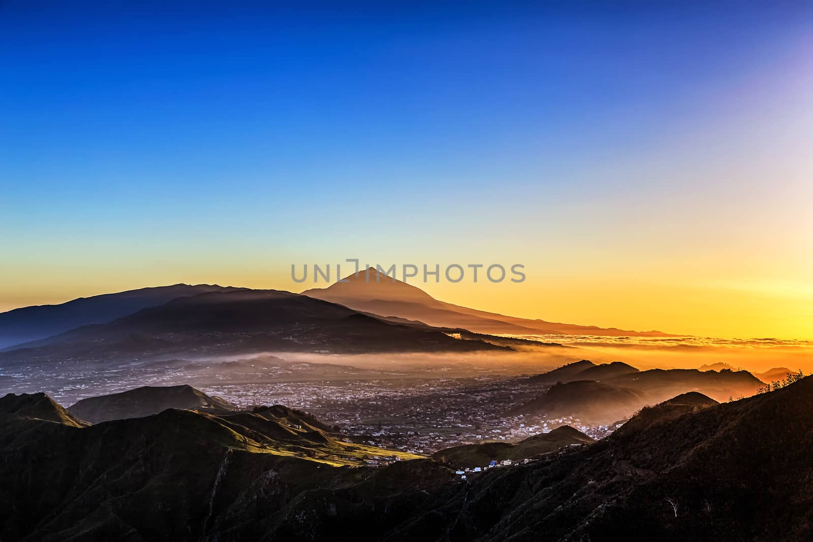 Evening sunset in mountains and blue sky with fog or haze and Teide volcano on background in Tenerife Canary island, Spain at spring or summer