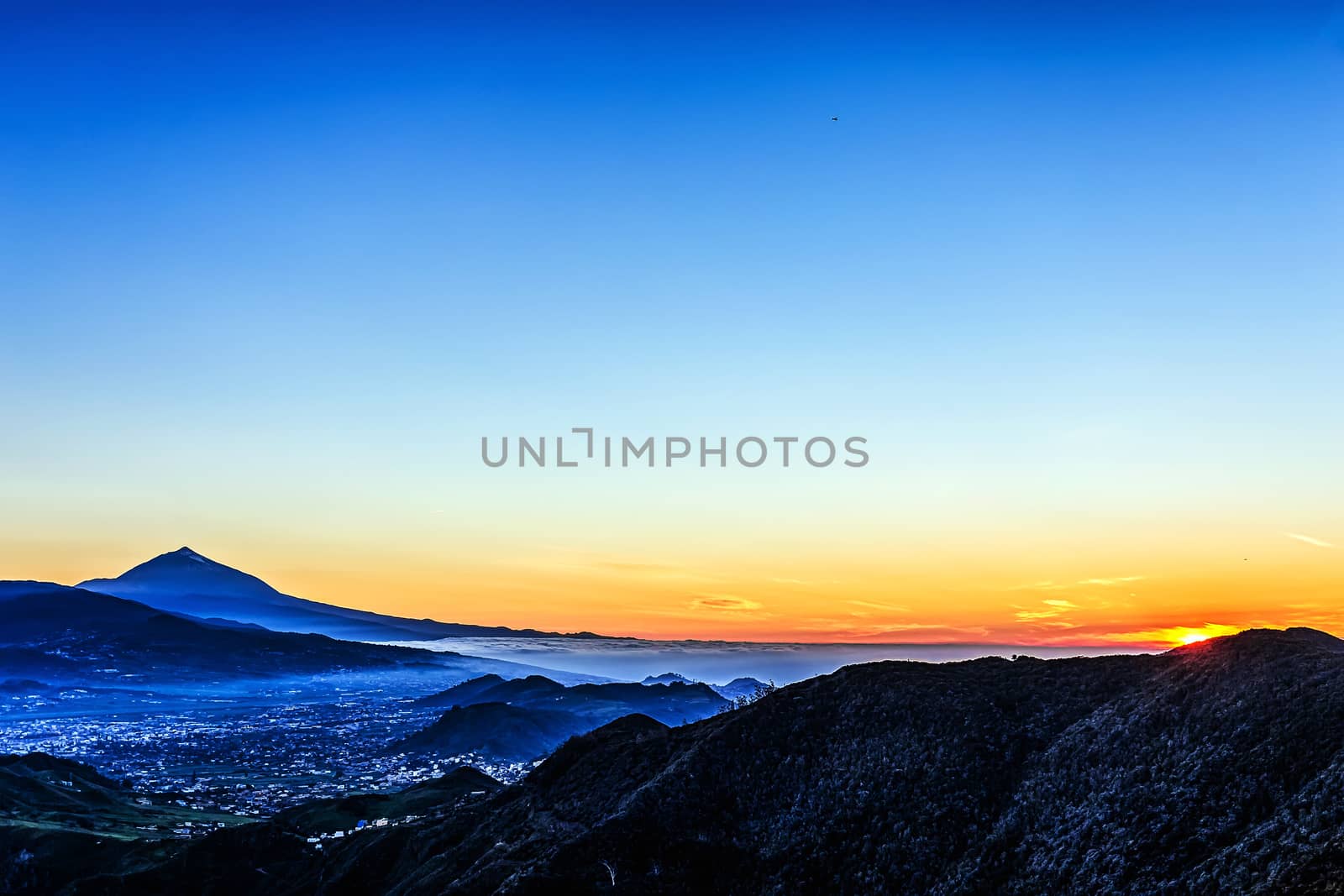 Sunset in mountains and blue sky with fog or haze and Teide volcano on background in Tenerife Canary island, Spain