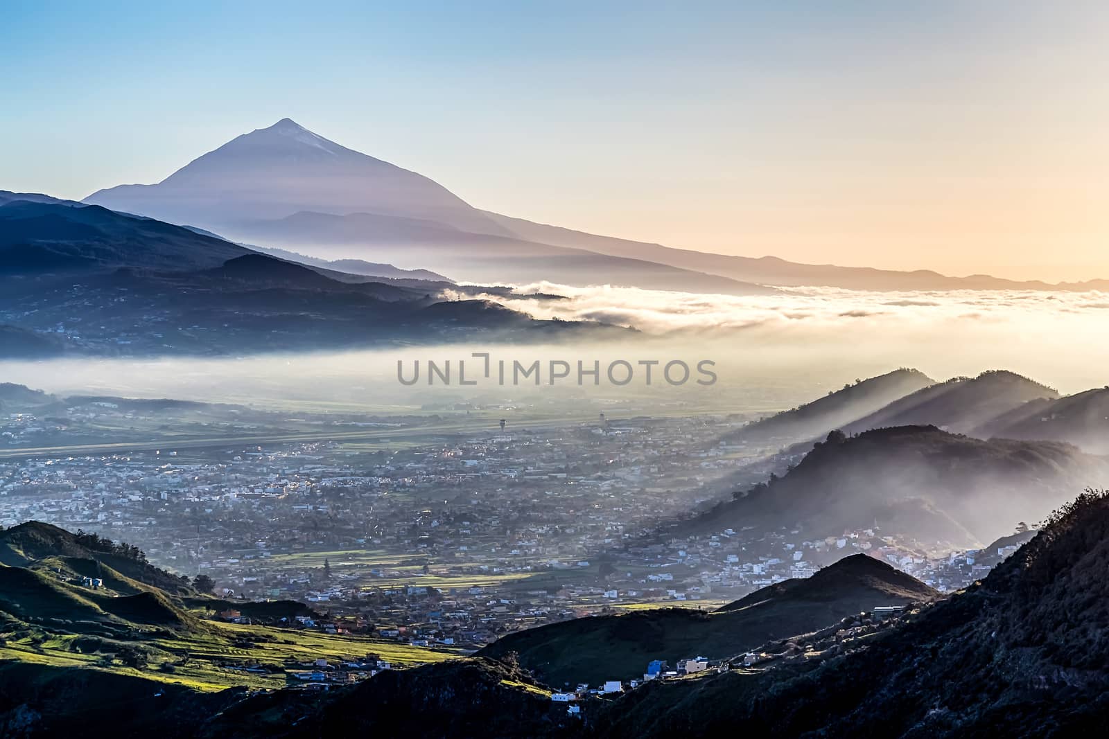 Sunset at evening in mountains and blue sky with fog or haze and Teide volcano on background in Tenerife Canary island, Spain