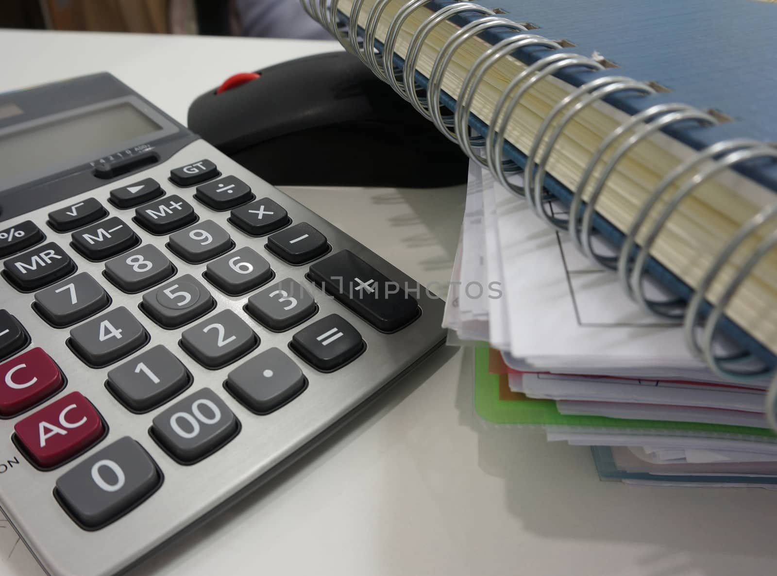 Notepad, file document and calculator placed on desk at office.                               