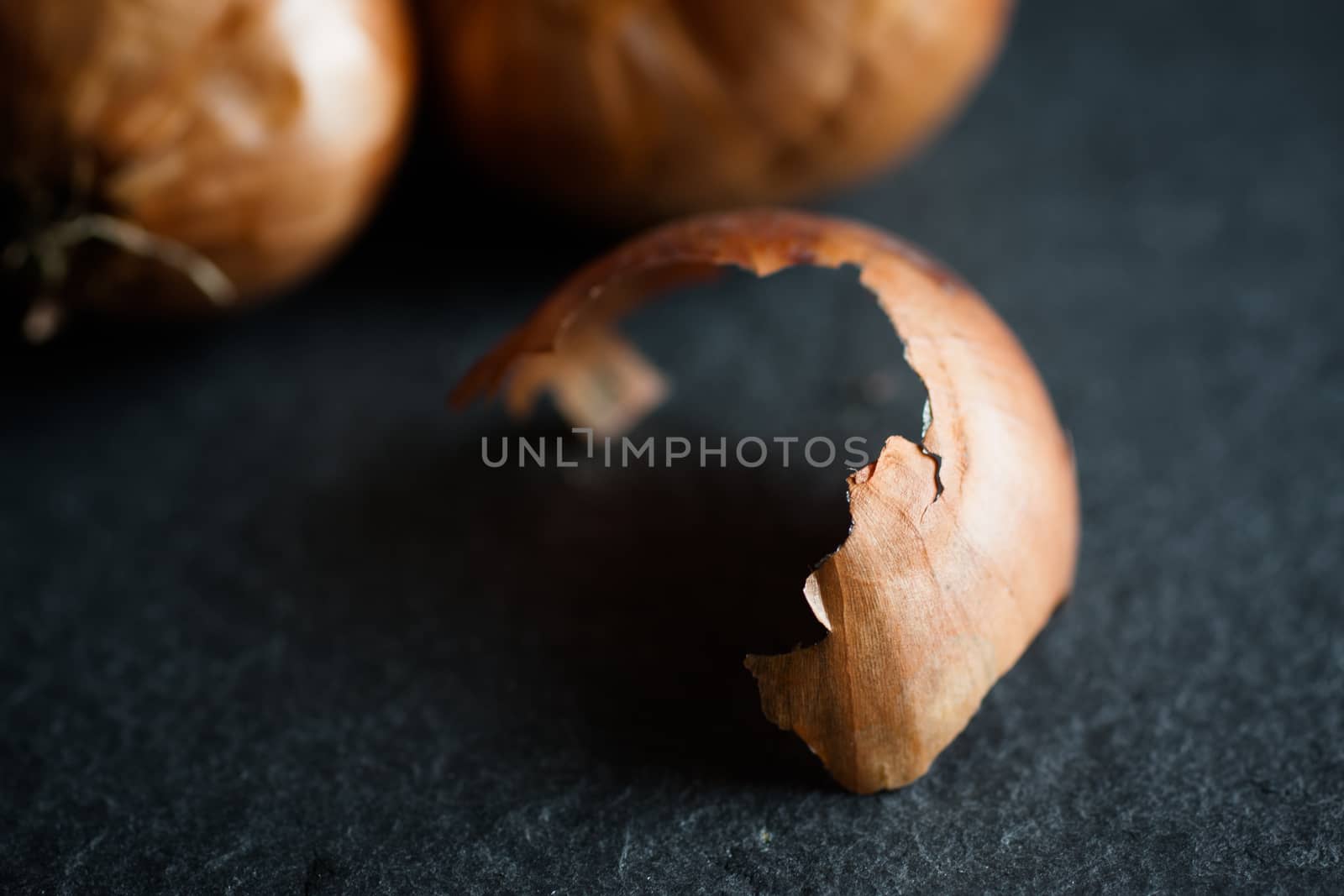 Shallots on a dark piece of slate in shados and sun.