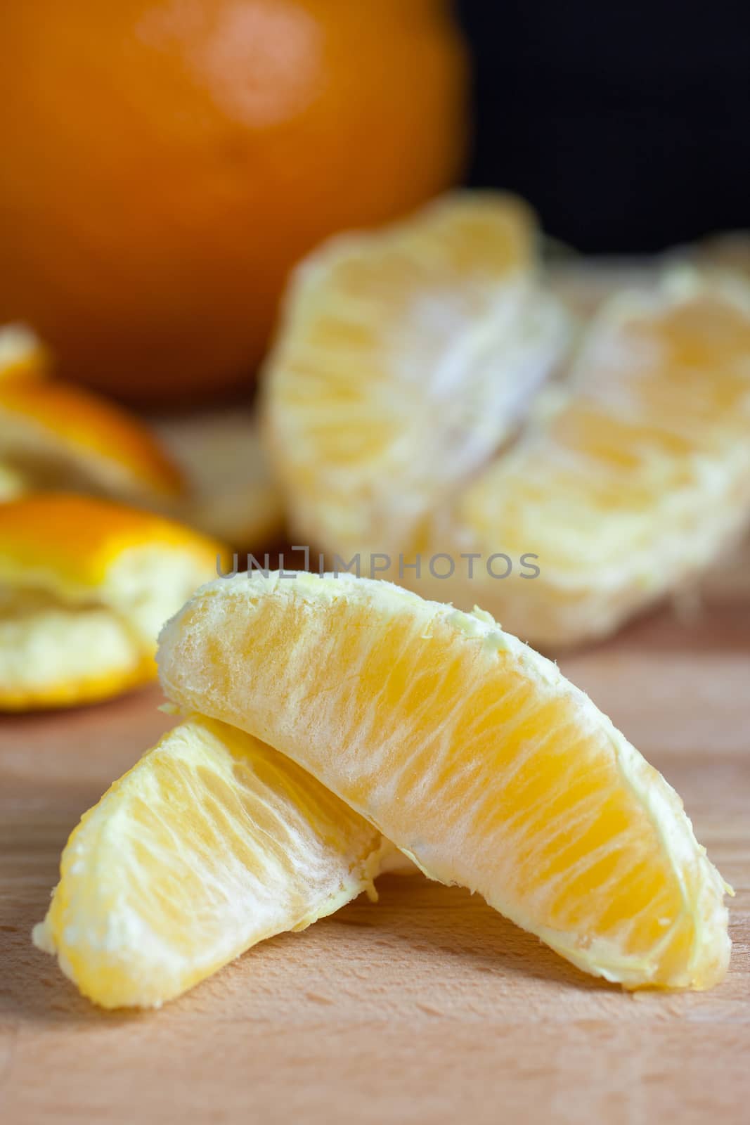 Peeled oranges on a wooded cutting board.