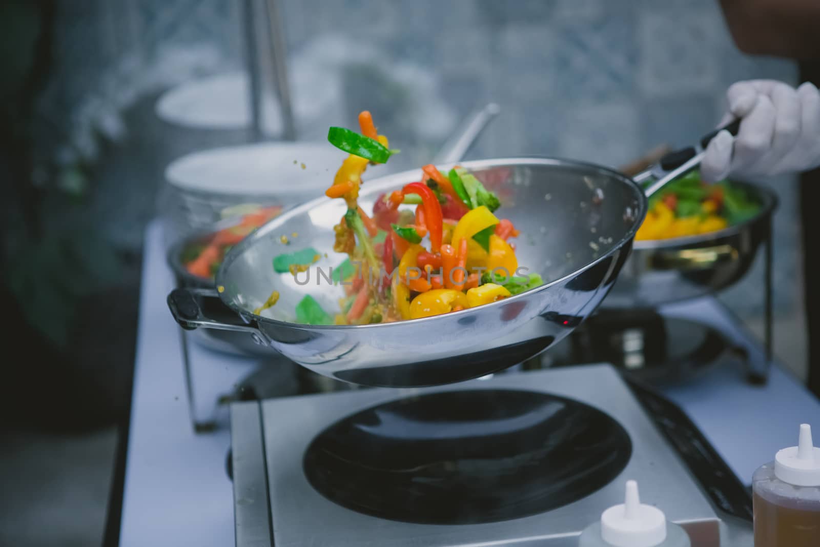 cooking vegetables in wok pan by sarymsakov