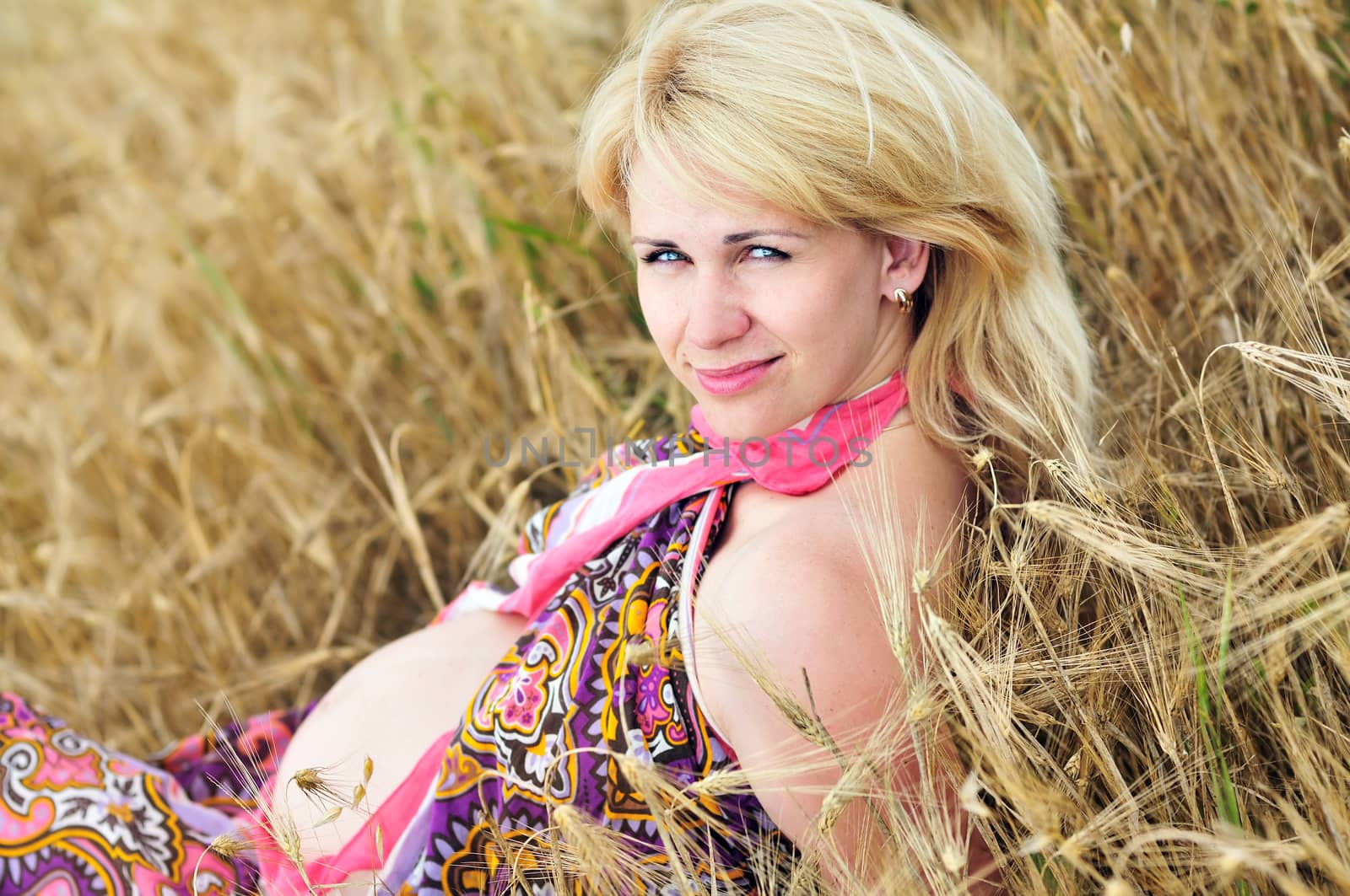 blonde pregnant woman relaxing in the wheat field 