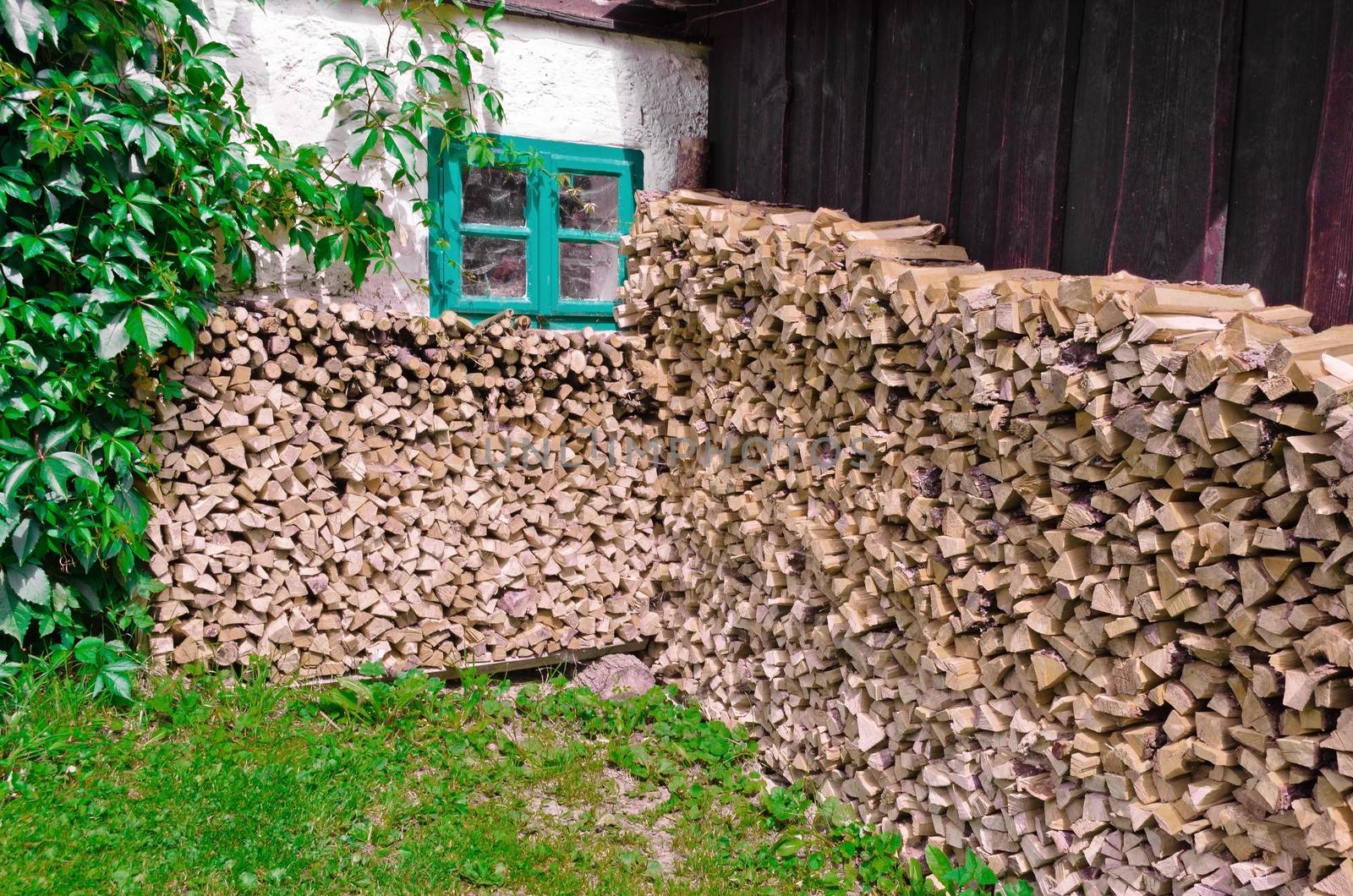 A pile of firewood under the window of country house