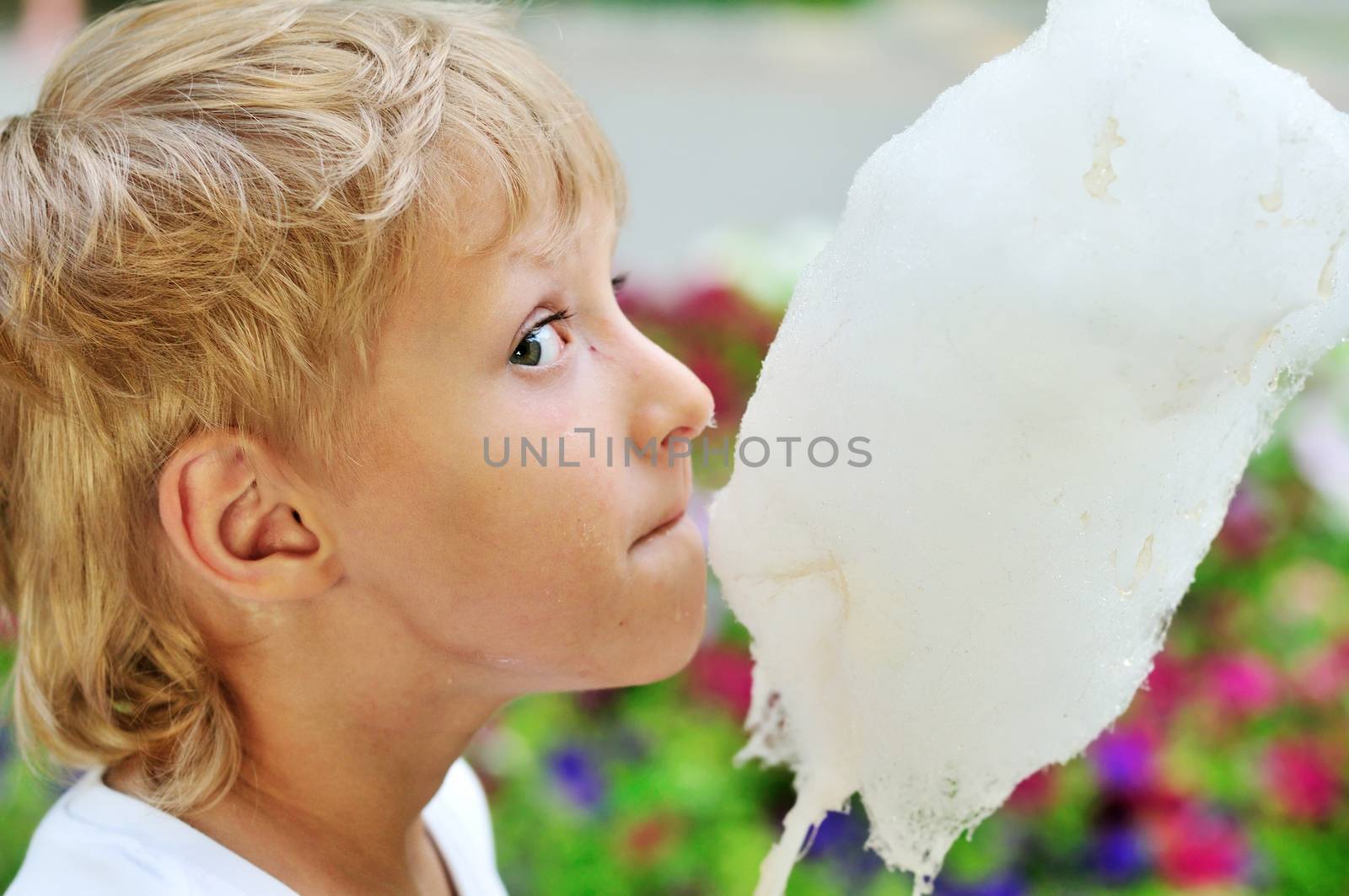 funny dirty face of little boy eating sweet cotton candy