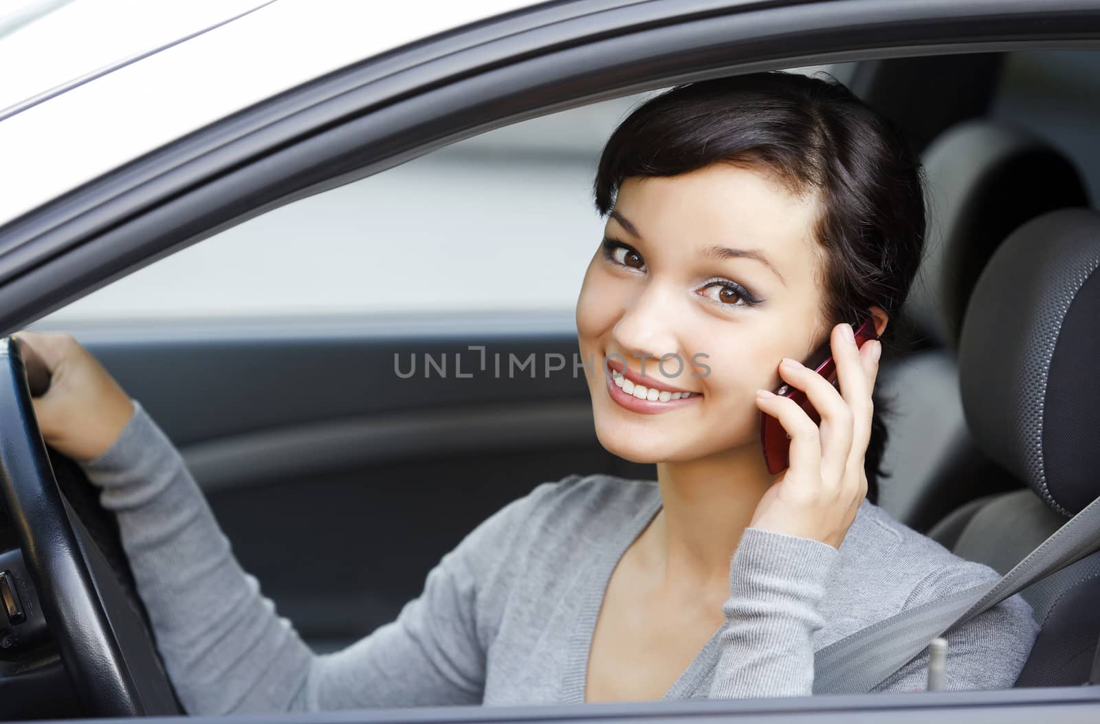 happy young woman talk on cell phone sitting in white car by Nobilior