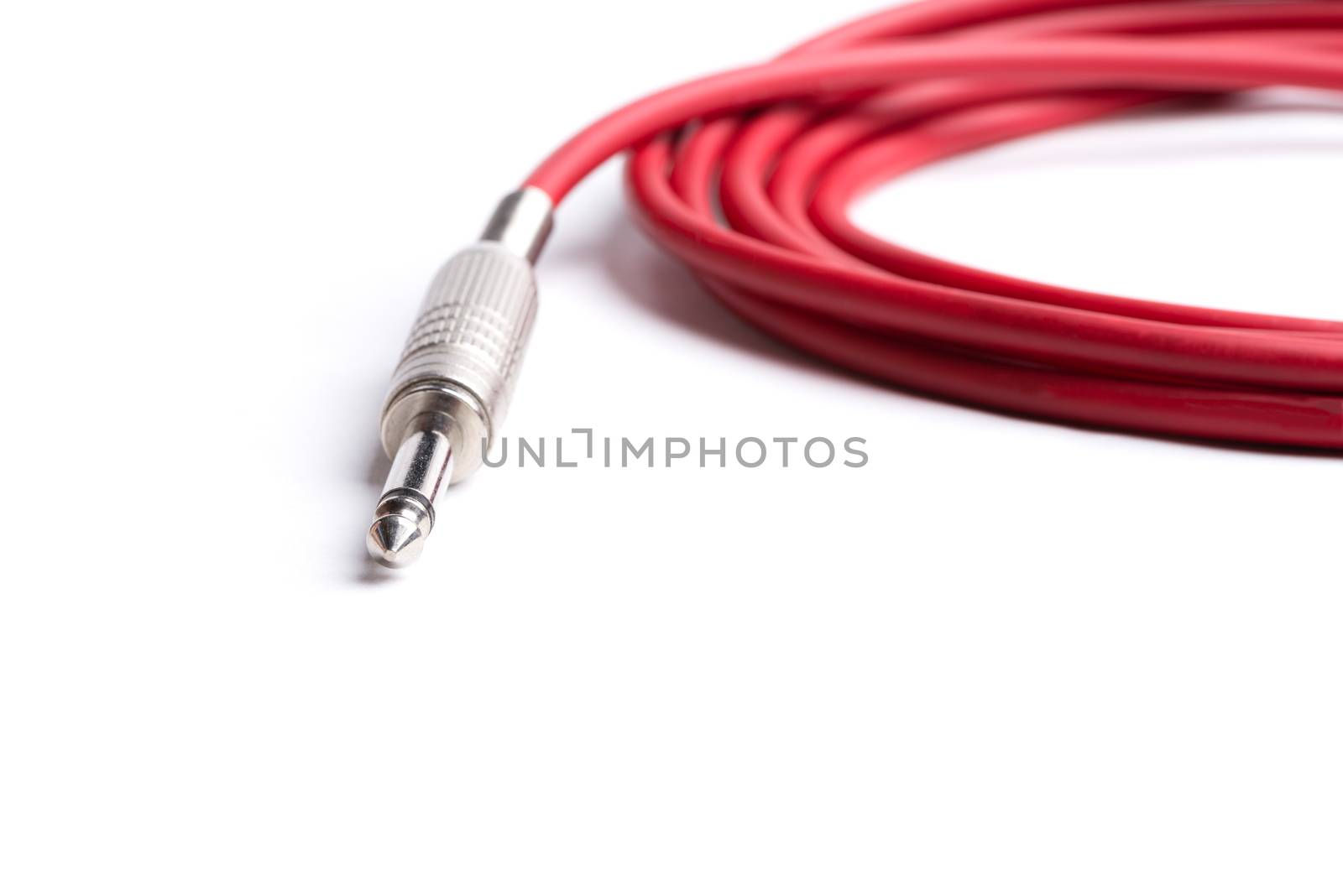 A red quarter inch cable for electric guitar isolated on a white background.