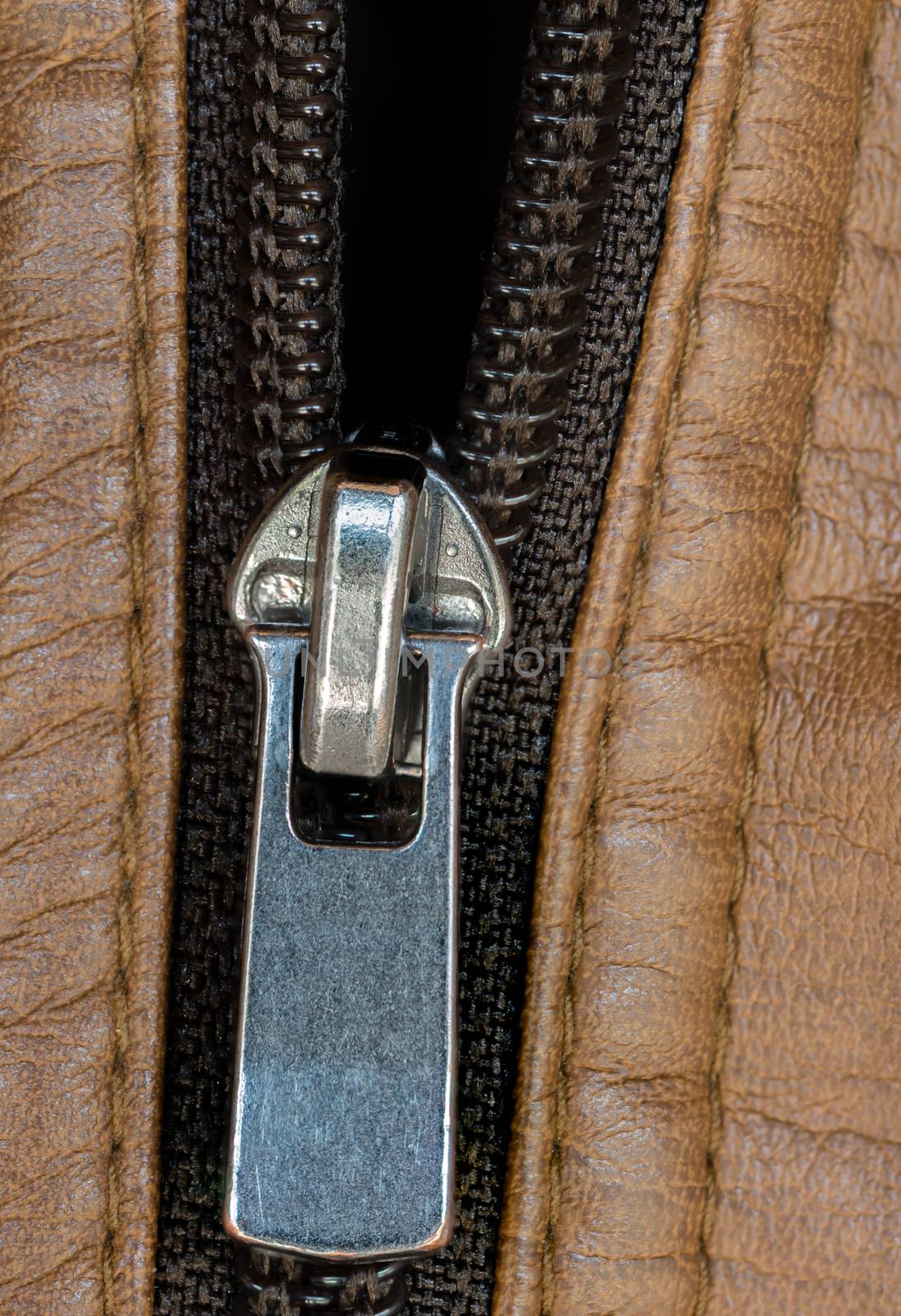 A macro shot of a zipper on a brown leather jacket.
