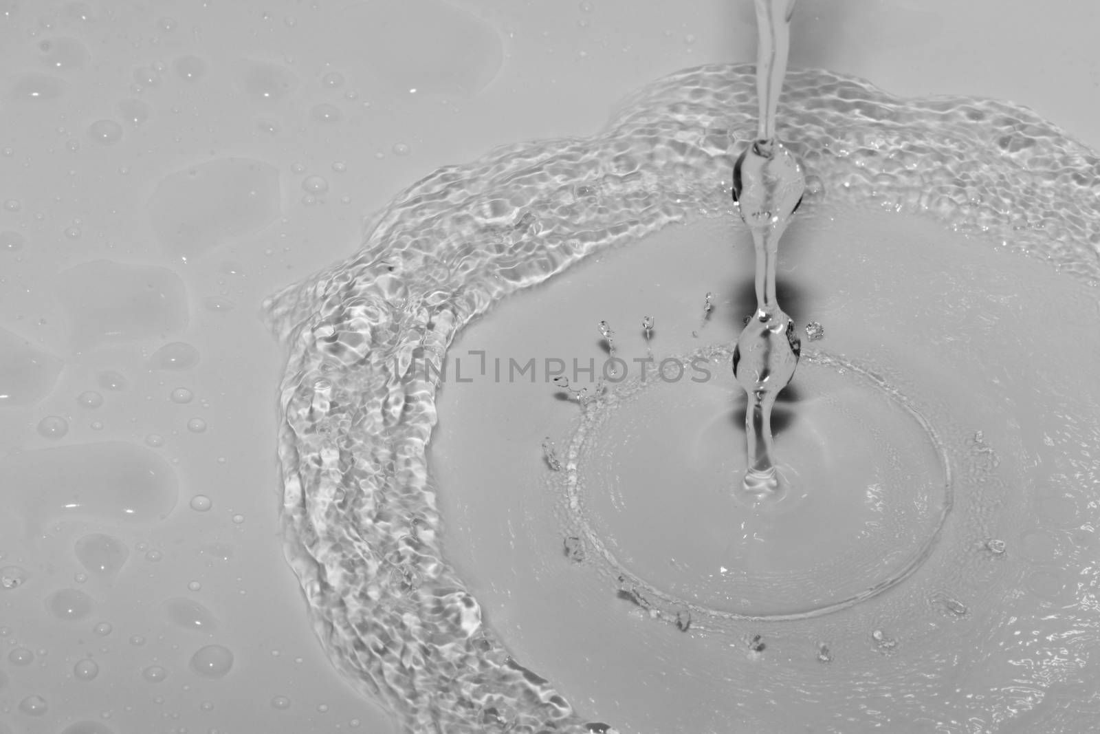 A stream of water splashing and making ripples in a white sink.