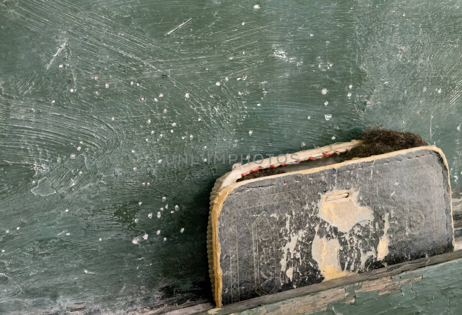 An old falling apart eraser on a green chalkboard.