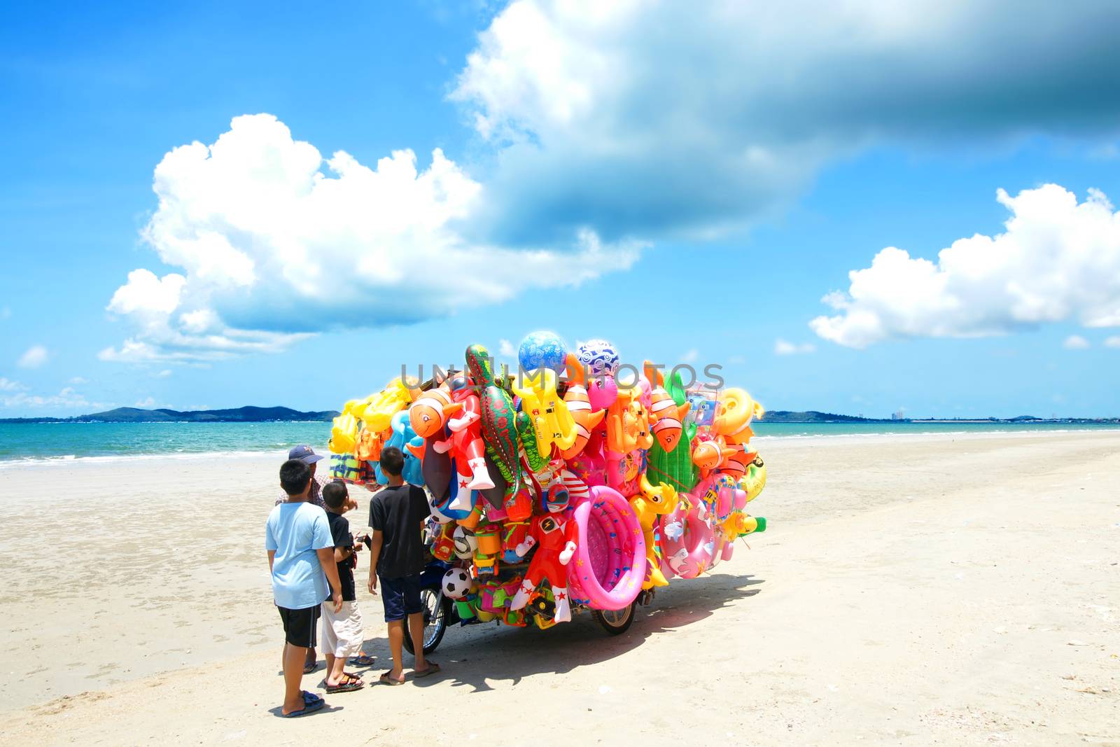 RAYONG,THAILAND-MAY 07,2015 :The man ride mobile shop selling toys to child on the beach in Eastern of Thailand.