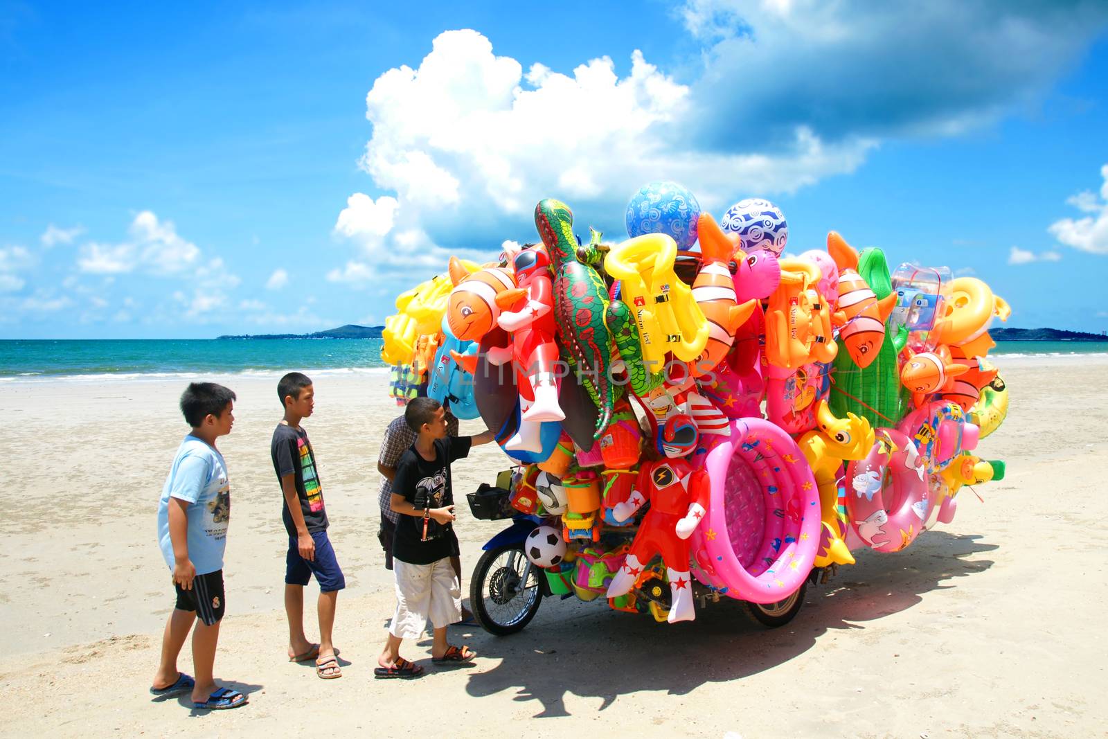 RAYONG,THAILAND-MAY 07,2015 :The man ride mobile shop selling toys to child on the beach in Eastern of Thailand.