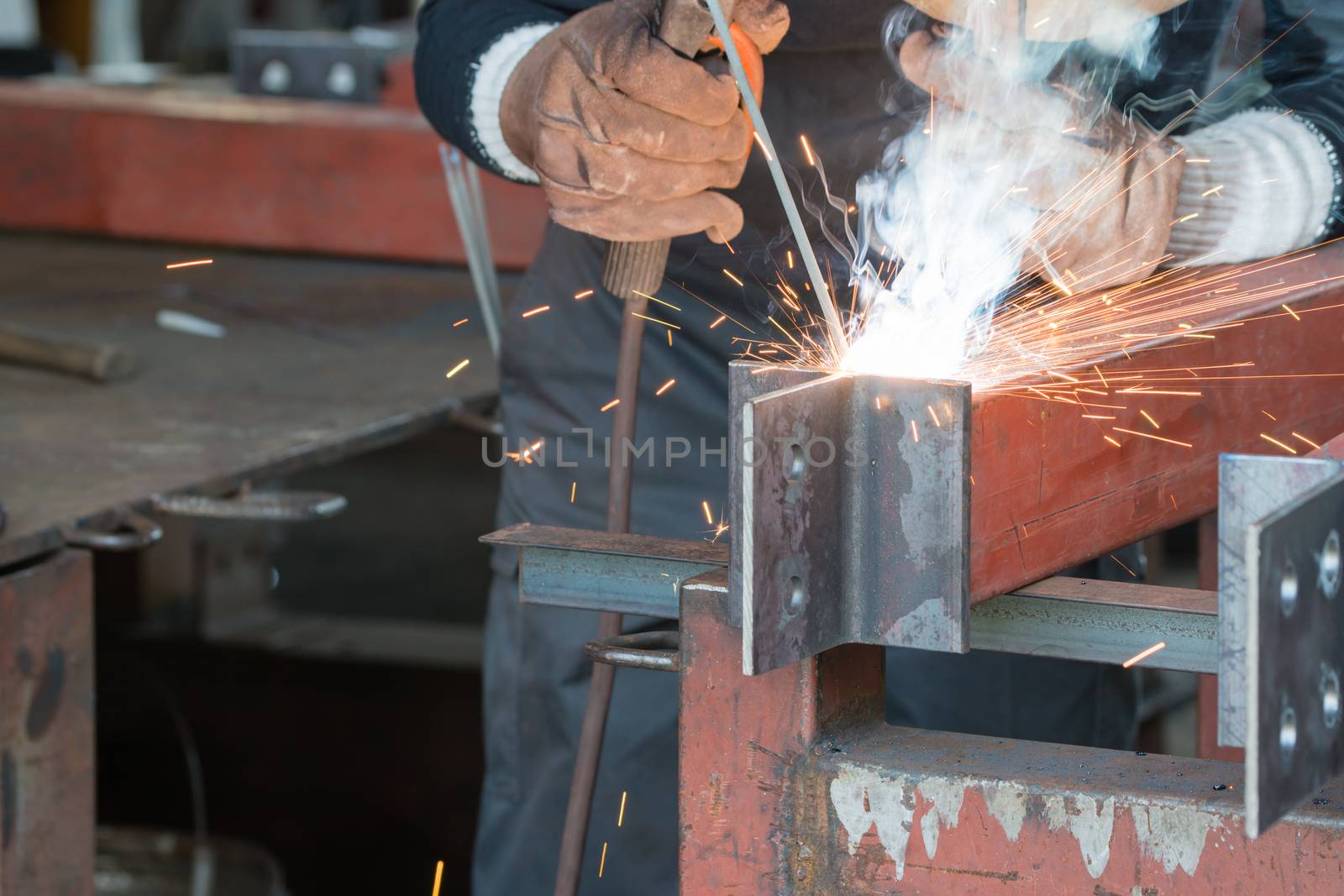 A welder welding creating sparks and smoke.