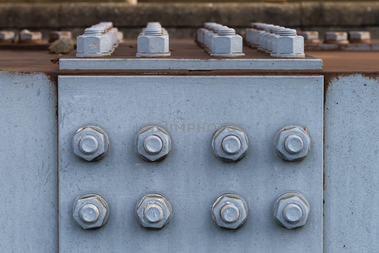 A close up of rusted nuts and bolts on a metal bridge.